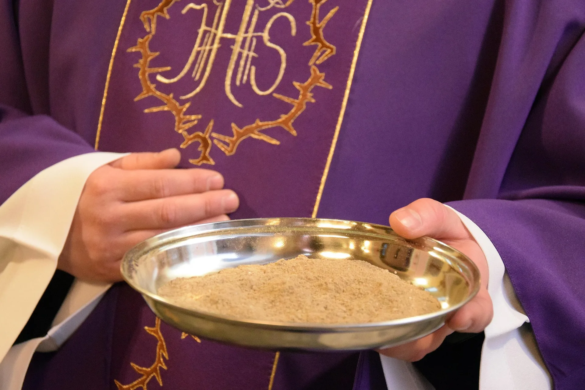 Priest in purple robes holding a bowl of ashes